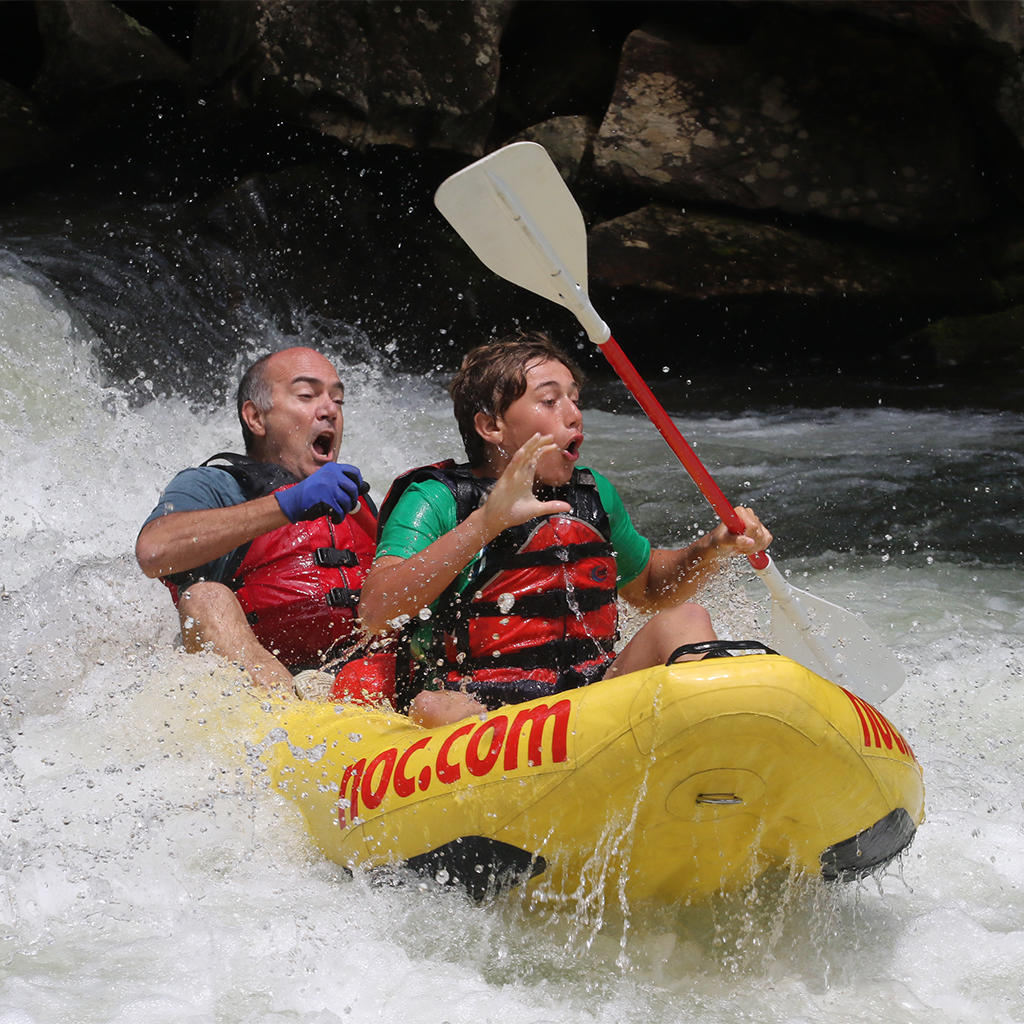 Two people white water rafting down a falls in a yellow raft